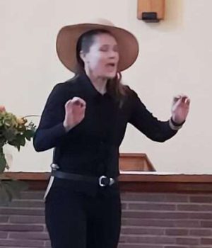 Schauspielerin in schwarzer Kleidung und Hut bei der Shakespeare-Aufführung in Randau